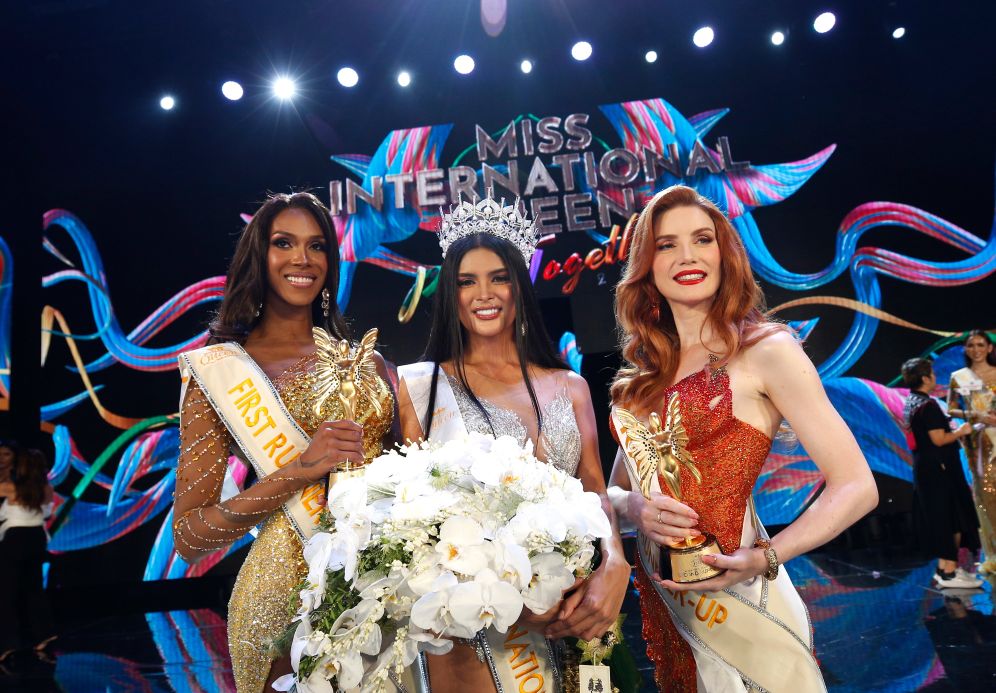 Miss International Queen pageant winners on stage with crown and trophies