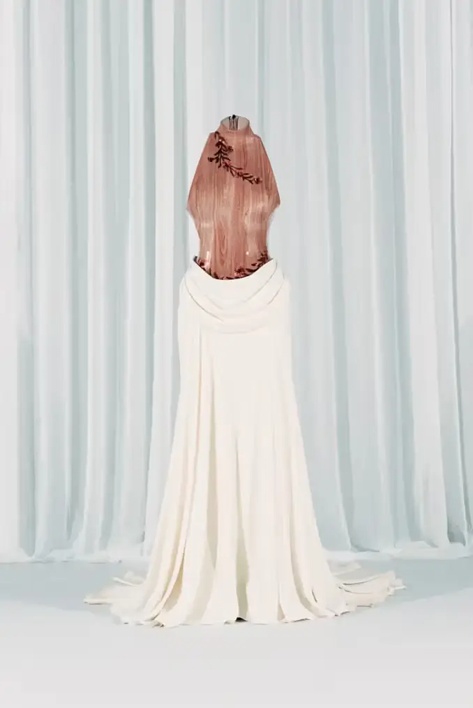 Elegant white wedding gown with rose gold metallic bodice and floral embellishments on mannequin