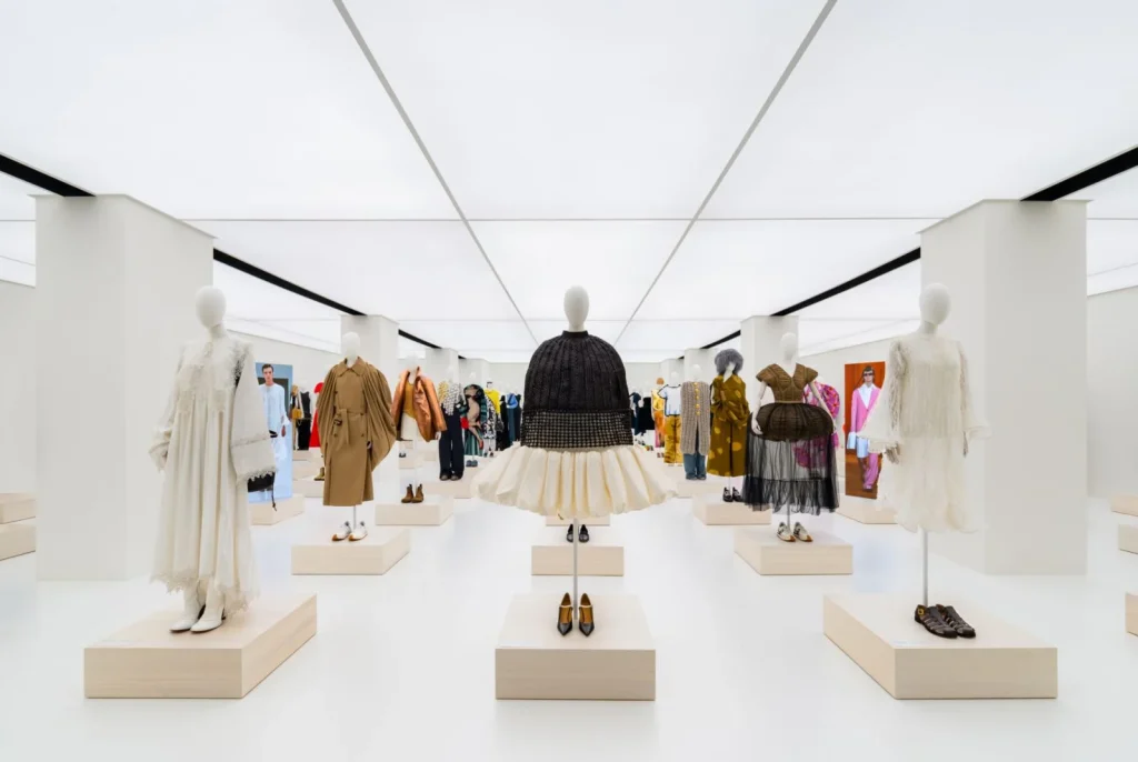 Fashion exhibition display with mannequins showcasing designer clothing collection in minimalist white gallery space