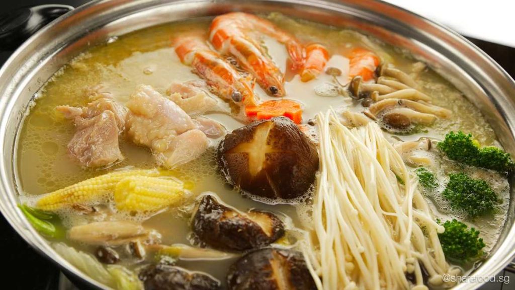 Asian hot pot with seafood, noodles, shiitake mushrooms, baby corn and broccoli in clear broth