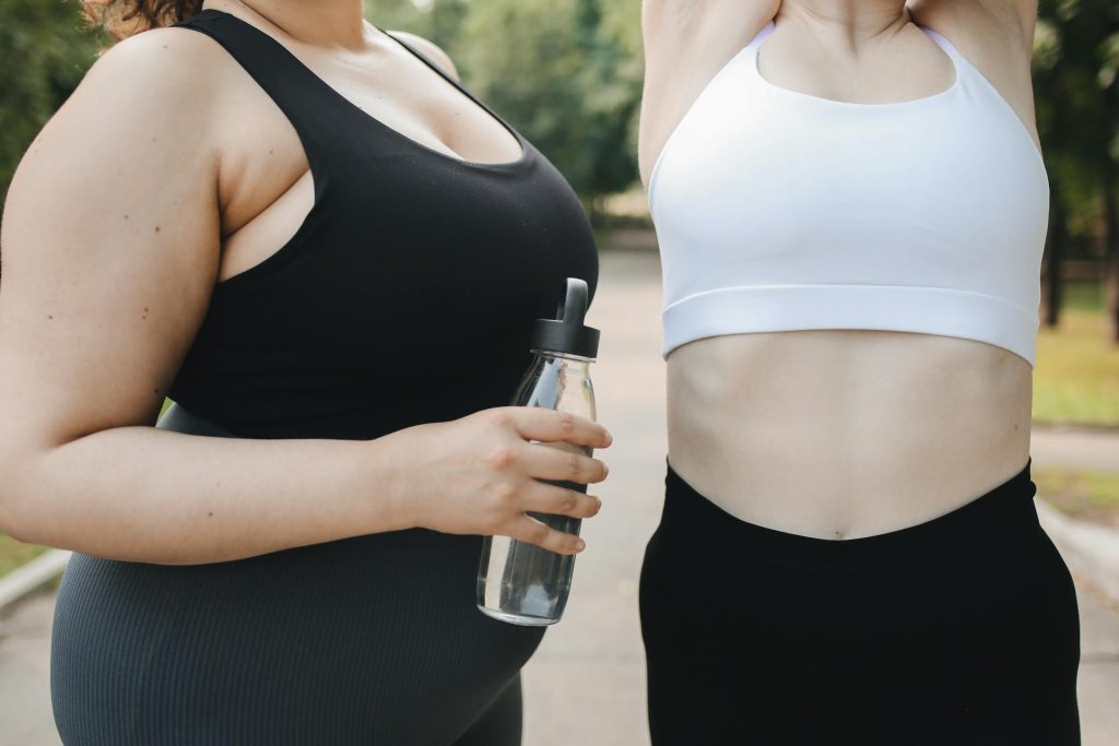 Two women in workout gear with water bottle during outdoor exercise