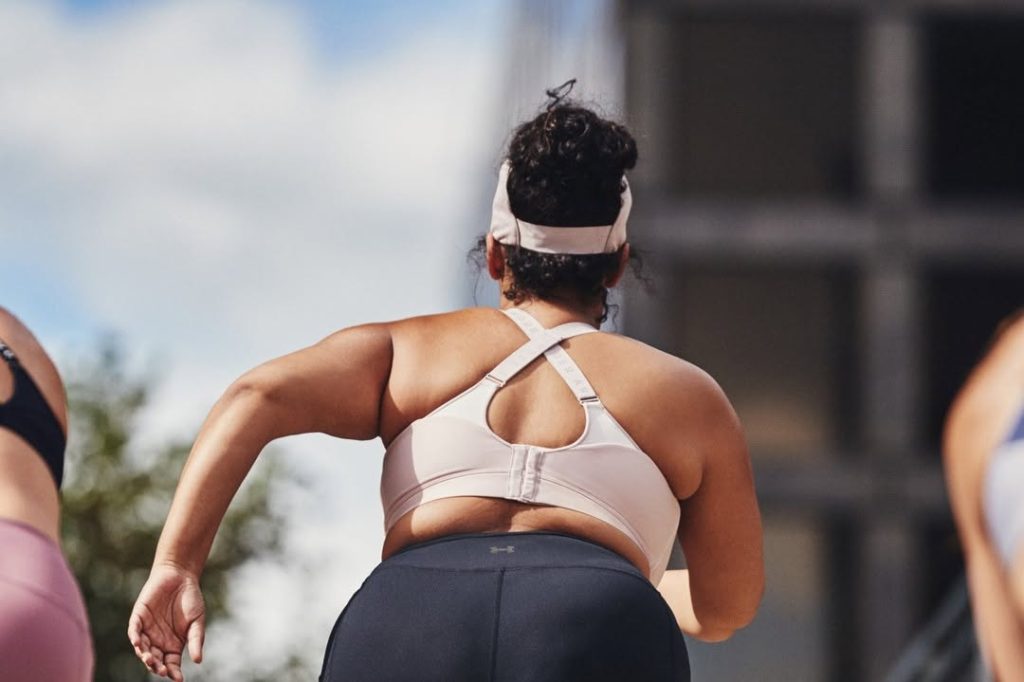 Back view of athlete in white sports bra and navy leggings wearing Under Armour apparel during outdoor workout