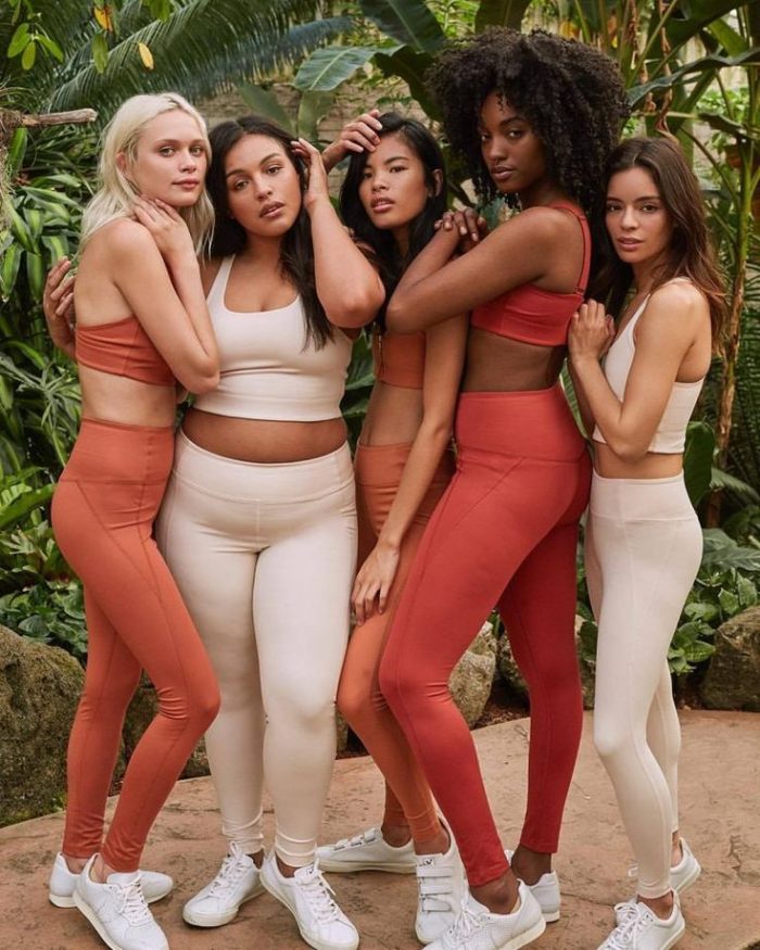 A group photo of a woman wearing orange and white activewear