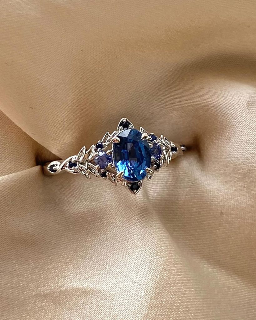 Blue sapphire engagement ring with diamond accents on satin fabric