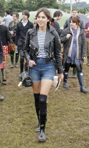 A photo of a girl wearing a white top, black jacket, blue maong shorts , black socks and shoes